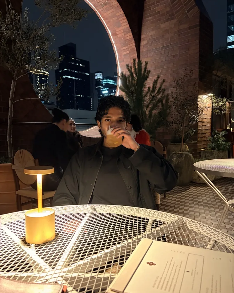 Shei, founder of MANA, at a rooftop table in Melbourne at night